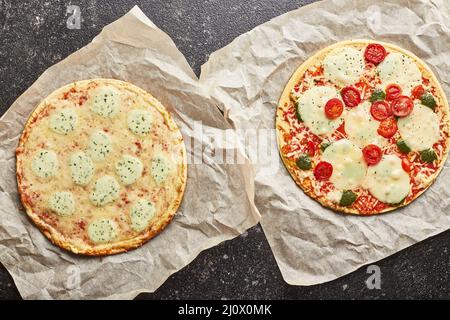 Fast Food, gebackene Tiefkühlpizza mit vier Käsesorten und Pizza mit Mozzarella-Käse, Tomaten und Pesto. Bereit zum Essen Stockfoto