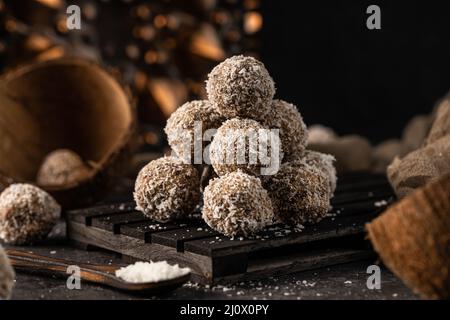 Stillleben Foto von gesunden, hausgemachten, leckeren Süßigkeiten. Leckere Kokosnussbällchen ohne Laktose und Zucker mit gesunden Zutaten Stockfoto