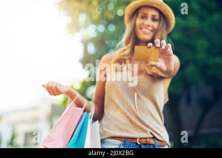 Legen Sie alles auf die Karte. Porträt einer attraktiven jungen Frau, die Ihnen ihre Kreditkarte zeigt. Stockfoto