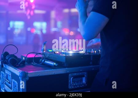 Nahaufnahme des DJ Mixer Controller Desk bei der Night Club Disco Party. DJ Hände berühren Tasten und Schieberegler spielen elektronische Musik . Stockfoto