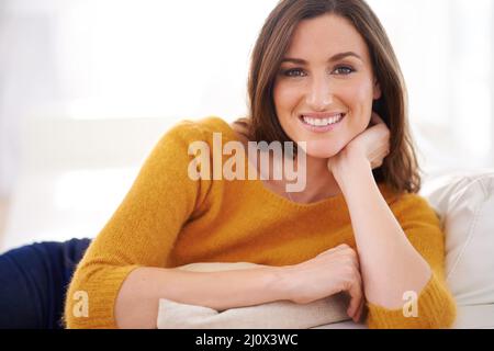 Ich bin viel zu komfortabel, um sofort aufzustehen. Porträt einer Frau, die drinnen sitzt und ihren Kopf auf der Hand hält. Stockfoto