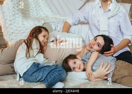 Familie mit zwei Kindern erwartet drittes Kind. Schwanger Mutter, Vater, Sohn und Tochter entspannen zu Hause. Stockfoto