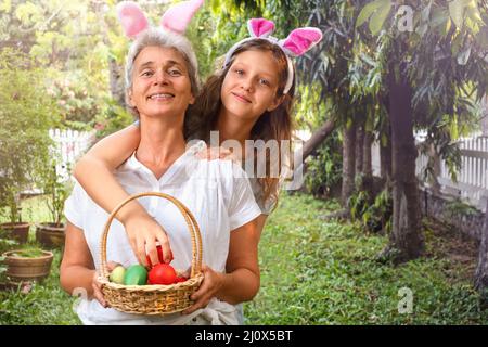 Glückliche ältere Frau und Teenager-Mädchen mit ostereiern im Korb im Freien Stockfoto