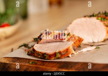 Gebacken im Ofen mit aromatischen Kräutern saftiges Schweinefilet In dünne Scheiben schneiden Stockfoto