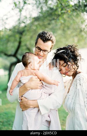 Frau, die ihren Kopf auf die Schulter eines Mannes legt, der ein Baby in den Armen hält Stockfoto