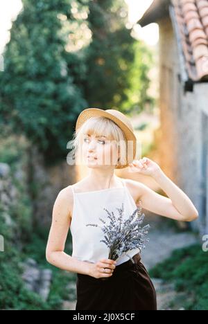 Frau in einem Strohhut mit einem Strauß Lavendel in der Hand. Hochformat Stockfoto