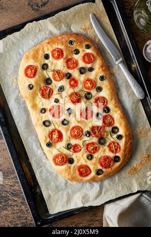 Focaccia, Pizza, italienisches Fladenbrot mit Tomaten, Oliven und Rosmarin auf Tablett Stockfoto