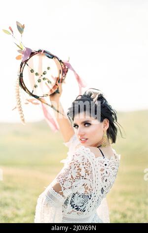 Mädchen in einem weißen Korbkleid hob ein Tamburin über ihren Kopf Stockfoto