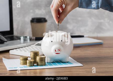 Wachstumskarte für die Hand Putting Coin Piggy Bank. Hochwertiges, schönes Fotokonzept Stockfoto