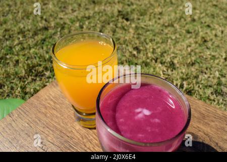 Granatapfelsaft und Orangensaft malta Saft in transparentem Glas auf weißem Hintergrund. Anaar Juice santra ras auf Holzbrett Stockfoto