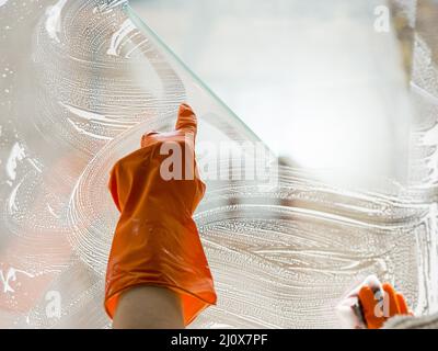 Nahaufnahme der Hand mit dem Reinigungsfenster mit Gummihandschuhen. Hochwertiges, schönes Fotokonzept Stockfoto