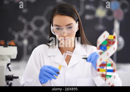 Fortschritte in der Genetik Verbesserung des Lebens. Aufnahme einer Wissenschaftlerin, die Flüssigkeit in ein Reagenzglas gießt. Stockfoto