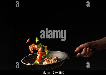 In einer Pfanne die Speckscheiben mit Knoblauch und scharfer Paprika und Brokkoli zubereiten Stockfoto