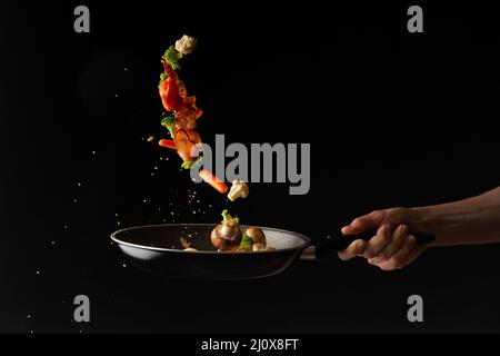 In einer Pfanne die Speckscheiben mit Knoblauch und scharfer Paprika und Brokkoli zubereiten Stockfoto