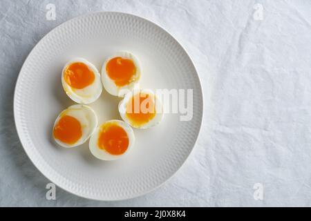 Weich gekochte Eier, geschält und in zwei Hälften geschnitten, auf weißem Teller liegend, kopieren Platz Stockfoto