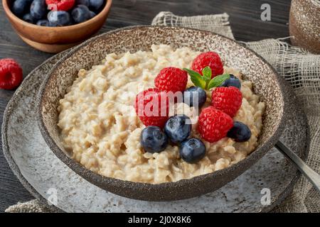 Haferbrei rustikaler Haferbrei mit Blaubeere, Himbeeren in einer klassischen Keramikschale, DASH-Diät mit Beeren Stockfoto