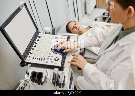 Nahaufnahme einer Ärztin, die ein Ultraschallgerät verwendet, während sie eine Schwangere in der Klinik untersucht Stockfoto