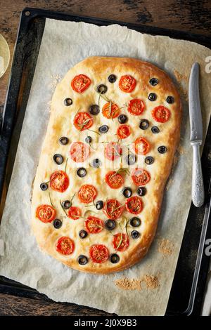 Focaccia, Pizza, italienisches Fladenbrot mit Tomaten, Oliven und Rosmarin auf Tablett Stockfoto