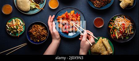 Set mit chinesischen Gerichten auf dem Tisch, weibliche Hände mit Essstäbchen Stockfoto