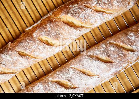 Frisch gebackenes hausgemachtes knuspriges Brot Baguette. Zwei Brote kühlen auf Metallrost ab Stockfoto