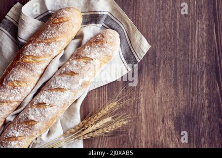 Frisch gebackenes hausgemachtes knuspriges Brot Baguette. Zwei Laibe auf Leinentuch Stockfoto