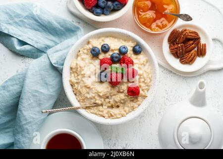 Haferbrei Haferbrei mit Blaubeere, Himbeeren, Marmelade und Nüssen, Draufsicht. Frühstück mit Beeren Stockfoto