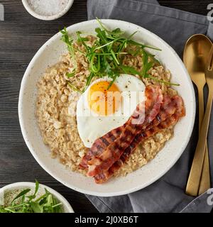 Haferflocken, Spiegelei und gebratener Speck. Brutales Männersportfrühstück. Herzhaftes, fettes Frühstück. Makro Stockfoto