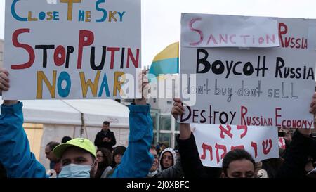 Tel Aviv, Israel. 20. März 2022. Demonstranten halten Zeichen gegen Russland und Putin, während sie sich versammeln, um eine Videoansprache des ukrainischen Präsidenten Volodymyr Zelensky vor dem israelischen parlament anzusehen, die am 20. März 2022 auf dem Habima-Platz in Tel Aviv, Israel, ausgestrahlt wurde. Zelenski forderte Israel auf, Sanktionen gegen Russland zu verhängen und der Ukraine zu helfen, indem er sich an Nazi-Deutschland erinnerte und sein Vorgehen mit der aktuellen Situation verglich. Kredit: Eddie Gerald/Alamy Live Nachrichten Stockfoto