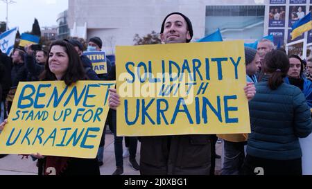 Tel Aviv, Israel. 20. März 2022. Demonstranten halten Plakate mit den Aufschriften „Bennett steht für die Ukraine“ und „Solidarität mit der Ukraine“, während sie sich versammeln, um eine Videoansprache des ukrainischen Präsidenten Volodymyr Zelensky vor dem israelischen parlament anzusehen, die am 20. März 2022 auf dem Habima-Platz in Tel Aviv, Israel, ausgestrahlt wurde. Zelenski forderte Israel auf, Sanktionen gegen Russland zu verhängen und der Ukraine zu helfen, indem er sich an Nazi-Deutschland erinnerte und sein Vorgehen mit der aktuellen Situation verglich. Kredit: Eddie Gerald/Alamy Live Nachrichten Stockfoto