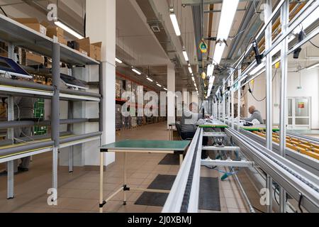 Minsk, Weißrussland - 15. Dezember 2021: Foto einer Anlage zur Montage von Monoblocks für Computer. Arbeiter arbeiten am Förderband Stockfoto