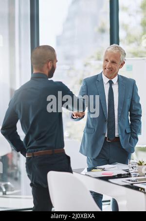 Ich gratuliere ihm zu seiner Arbeit, Gut gemacht. Eine kurze Aufnahme von zwei Geschäftsleuten, die im Büro die Hände schüttelten. Stockfoto