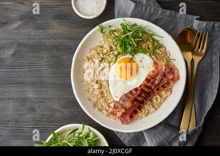 Haferbrei, gebratenes Ei und gebratener Speck. Brutales Mann-Sport-Frühstück. Ausgewogene Lebensmittel. Kopierbereich Stockfoto
