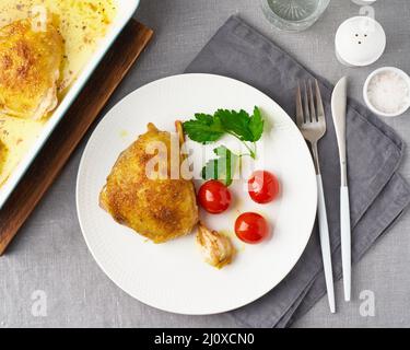 Hähnchenschenkel gebacken mit Kurkuma, Tomaten und Knoblauch. Gebratenes Huhn ist auf dem Teller Stockfoto