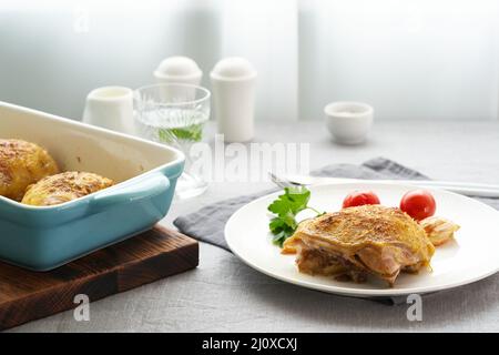 Hähnchenschenkel gebacken mit Kurkuma, Tomaten und Knoblauch. Gebratenes Huhn ist auf dem Teller Stockfoto