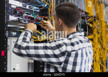 Junger Mann, der an einem ethernet-Switch arbeitet. Hochwertige Fotos Stockfoto