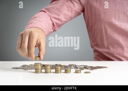 Mann stapelt Münzschreibtisch Stockfoto