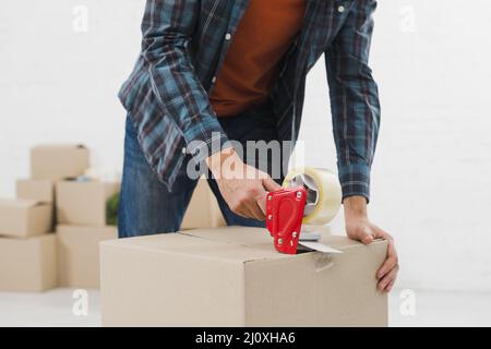 Nahaufnahme Mann versiegelt Karton mit Klebeband. Hochwertiges, schönes Fotokonzept Stockfoto