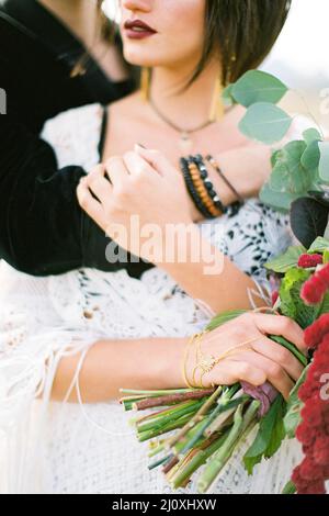 Bräutigam Umarmungen von hinten Braut mit einem Blumenstrauß. Hochformat Stockfoto