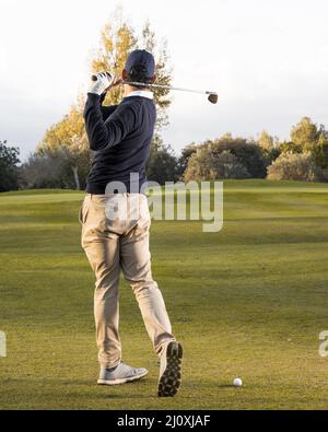 Rückansicht Mann, der auf einem grasbewachsenen Golfplatz spielt. Hochwertige Fotos Stockfoto