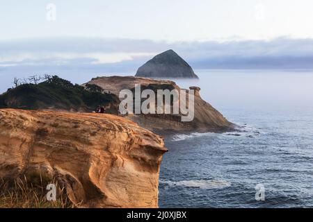 Ein Paar beobachtet den Sonnenuntergang an der Küste von Oregon am Cape Kiwanda in Pacific City Stockfoto