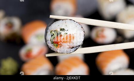 Nahaufnahme von Essstäbchen mit Sushi-Rolle. Hochwertiges, schönes Fotokonzept Stockfoto