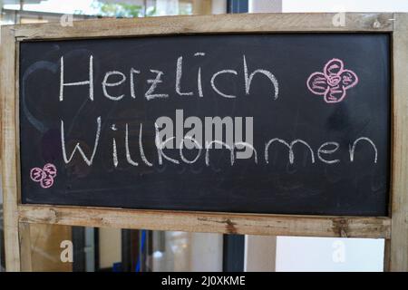 Outdoor-Tafel mit dem deutschen Text 'Herzlich willkommen', der in englischer Sprache in 'Herzlich willkommen' übersetzt wird Stockfoto