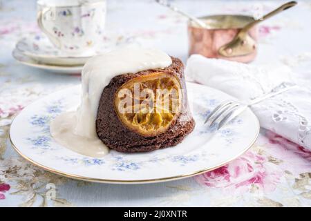 Traditioneller Orangenschokoladenkuchen mit Rum-Vanille-Sauce als Nahaufnahme auf einem Designteller Stockfoto