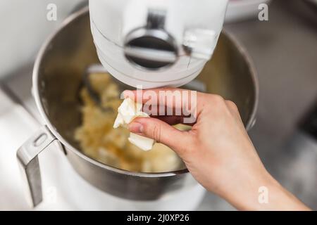 Nahaufnahme einer Frau, die Butter in einen Mixer gegeben hat Stockfoto