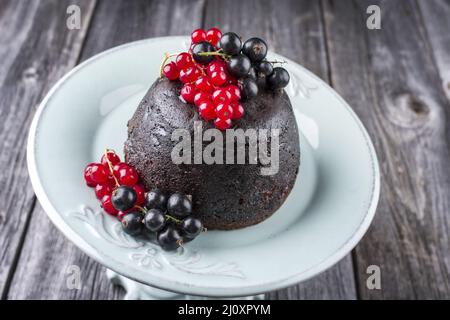 Traditionelle australische Pflaumenpudding frische Waldbeeren wurden als Nahaufnahme auf einem Design-Teller auf einem Holztisch angeboten Stockfoto