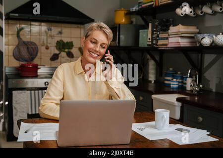 kaukasische ältere Frau, die von zu Hause aus am Mobiltelefon spricht Stockfoto