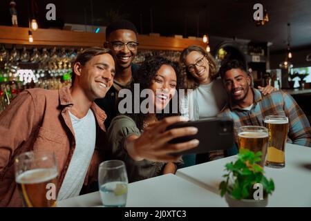 Eine Gruppe von jungen erwachsenen Freunden, die im Restaurant zu Abend essen und Selfies machen Stockfoto