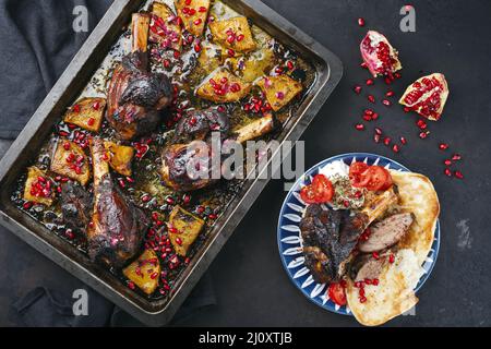 Traditioneller geschmorter, langsam gekochter australischer Lammschenkel mit Ananas und Granatapfel, serviert als Rückenansicht von oben Stockfoto