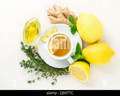 Traditionelle Methoden zur Behandlung von Erkältungen - Tasse Tee und eine Scheibe Zitrone, Ingwer, Minze, Honig, Kräuter, Ganze Zitronen und die Hälfte auf einem weißen Hintergro Stockfoto