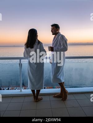 Ein Paar, ein Mann und eine Frau, die während des Sonnenaufgangs auf dem Balkon Kaffee trinken, während eines Urlaubs in Kapstadt, Südafrika Stockfoto